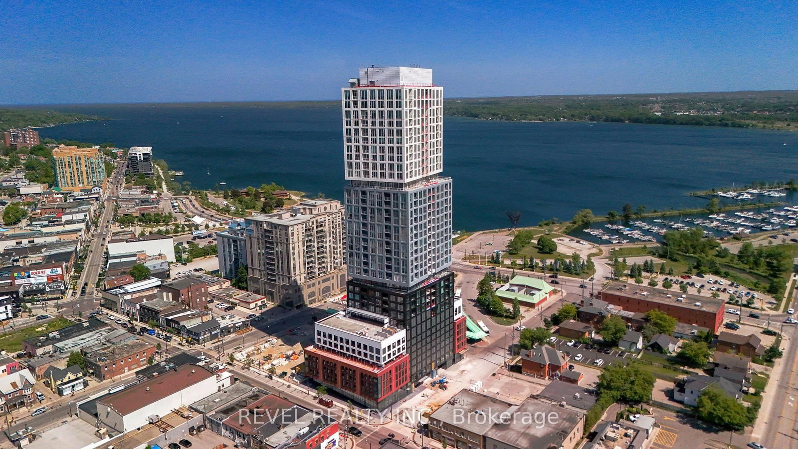 Discover elevated living in this stunning 1 bedroom suite at DEBUT Condos, Barrie's premier waterfront residence. Located on one of the building's highest floors, this beautifully appointed unit offers breathtaking panoramic views of the city skyline from the 29th floor, with a private balcony that provides the perfect setting for morning coffee or evening sunsets overlooking downtown Barrie. Inside, the thoughtfully designed layout begins with an extended entryway den space offering flexible space ideal for a home office nook or additional storage. The open concept living and kitchen area is filled with natural light through floor to ceiling windows, creating a bright and inviting atmosphere throughout. The sleek modern kitchen features hidden built in appliances, stylish countertops with a continuous backsplash, and a convenient movable island for added functionality. The spacious bedroom and den are complemented by a beautifully finished 3 piece semi ensuite bath with elegant glass shower doors. Contemporary, tasteful finishes carry throughout the suite, offering a sophisticated and comfortable place to call home. Residents will also enjoy access to an exceptional collection of hotel inspired amenities, including an infinity plunge pool with lake views, state of the art fitness centre, concierge service, outdoor lounge with fire pit, business centre, and more. Enjoy being just steps from Barrie Waterfront, the marina, downtown restaurants, shops, transit, and convenient access to Highway 400. One parking space included.